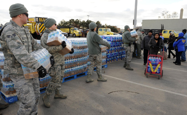 men in uniforms help bring water to people in need.